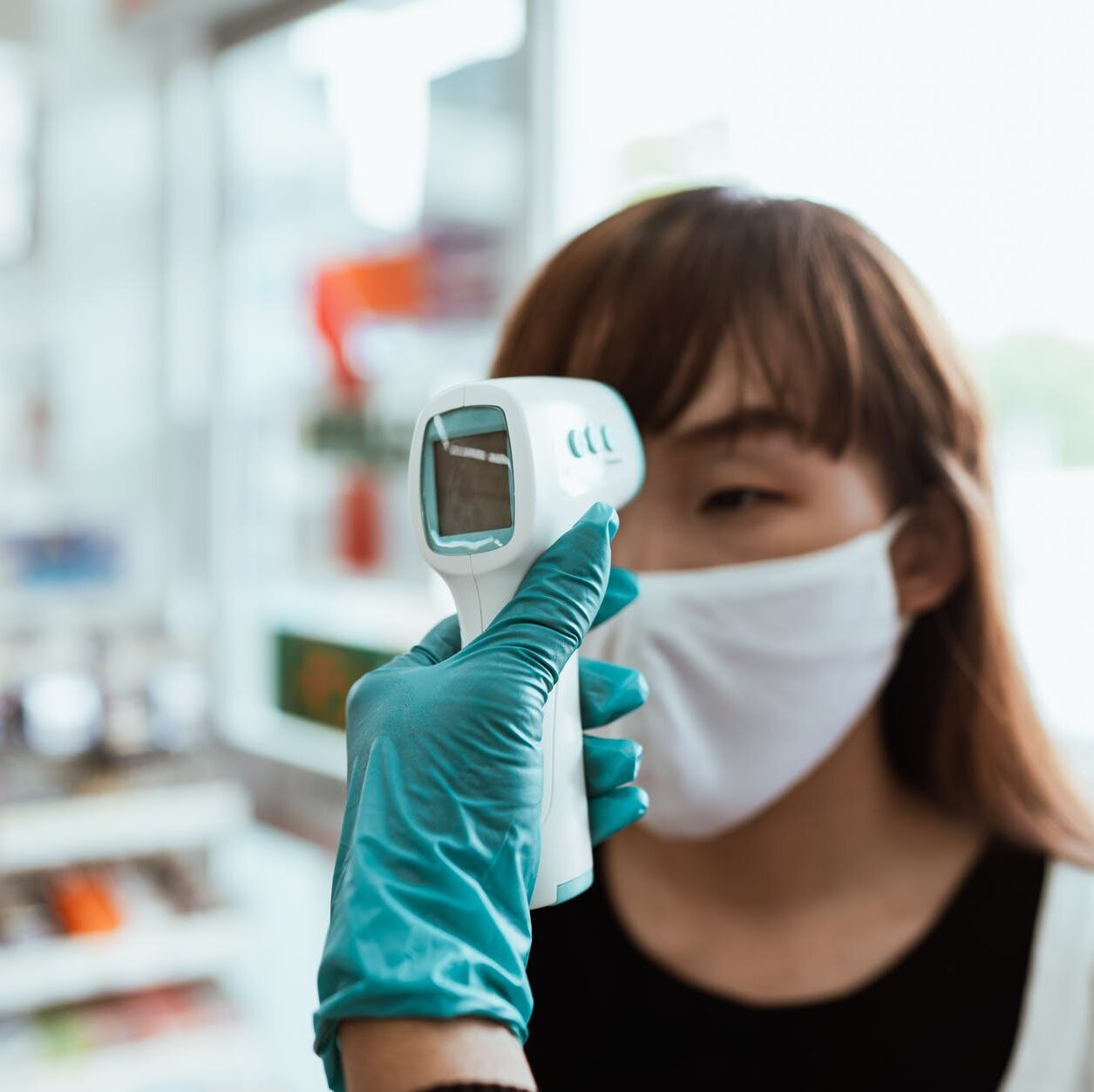 woman wearing a face mask getting her temperature checked